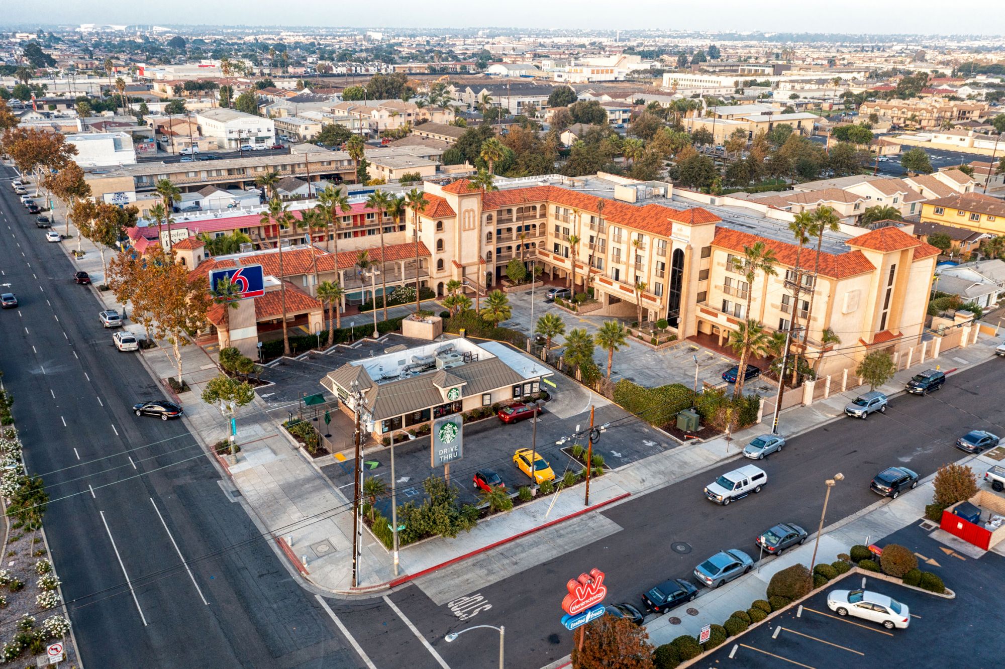 An aerial view of an urban area featuring buildings, roads with vehicles, trees, and a blend of residential and commercial establishments.